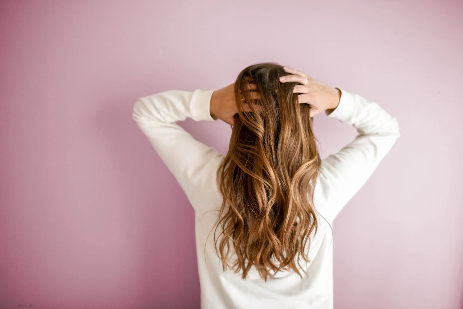 Balayage hair color with warm caramel tones transitioning from dark roots to lighter ends, back view