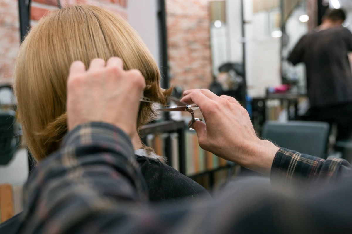 Hairstylist cutting a client's bob haircut in a salon, close-up on hands
