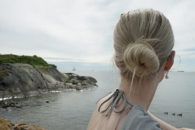 Low twist-and-wrap bun hairstyle with coastal cliffside and sea in the background