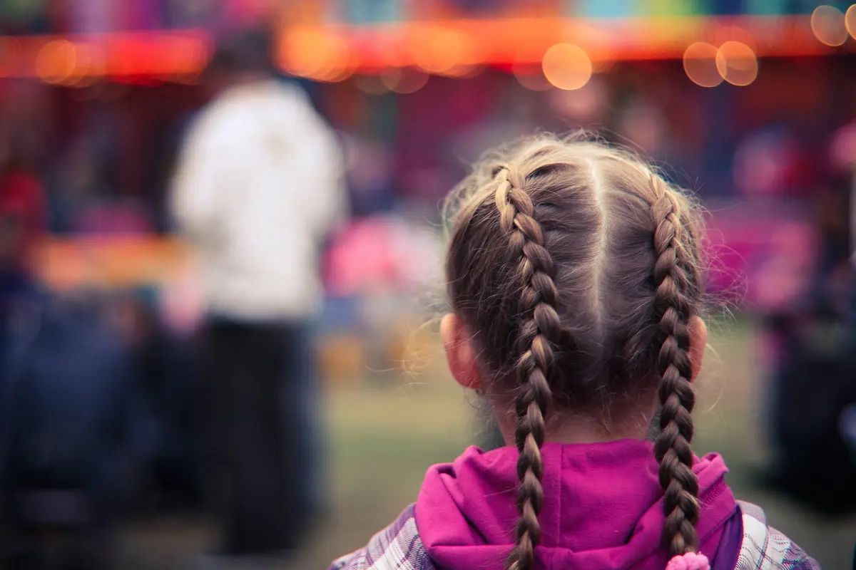Two raised Dutch braid pigtails with visible ridge texture, evening lights background