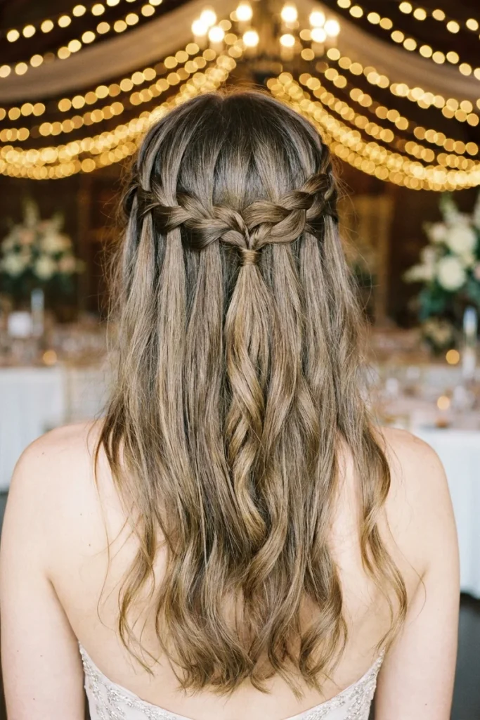 waterfall braid half-up hairstyle with cascading waves, back view, formal prom venue setting