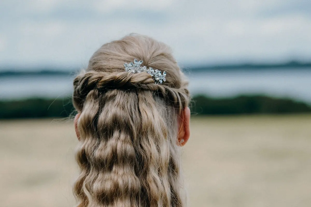 Half up half down hairstyle with twisted crown section and loose curled waves below