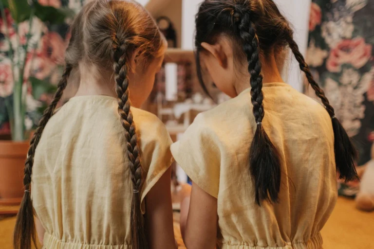 Two young girls with long braided pigtails viewed from behind, candid kids hairstyle inspiration
