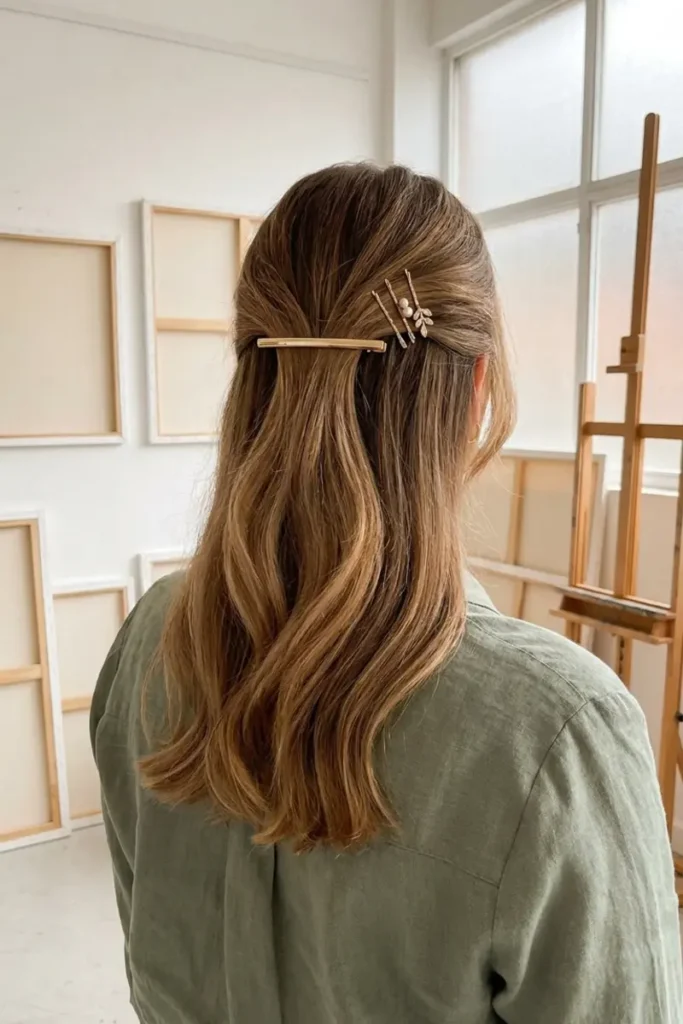 Half-up hairstyle with slim gold barrette and decorative pearl bobby pins securing top section