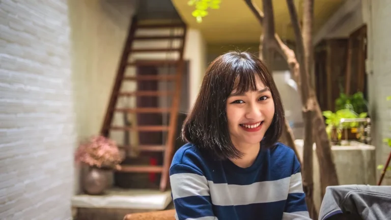 Woman with a soft blunt bob haircut and bangs smiling in natural indoor light