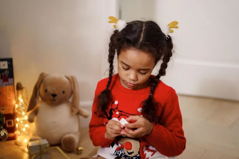 Little girl in red sweater with reindeer antler pigtail clips for Christmas hairstyle
