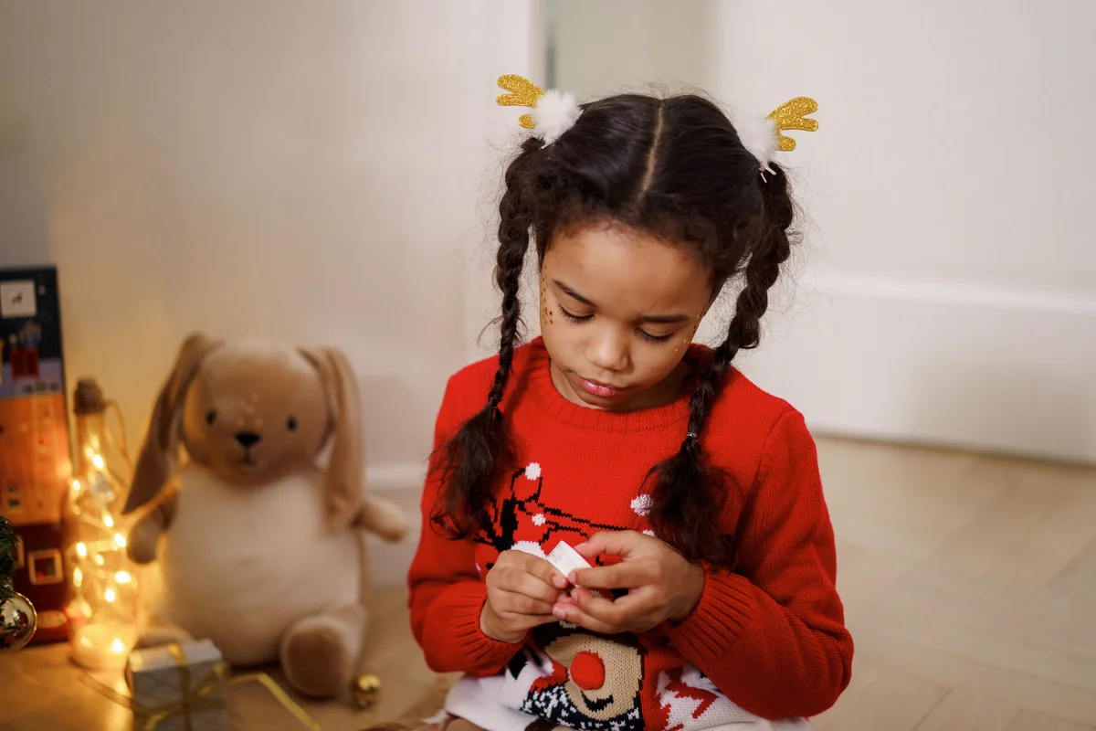 Little girl in red sweater with reindeer antler pigtail clips for Christmas hairstyle
