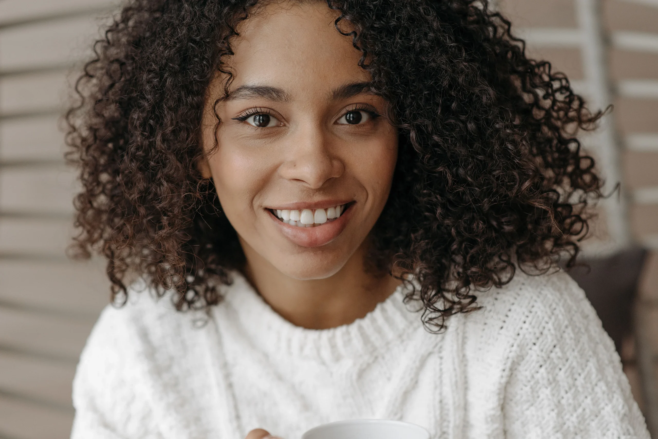 Woman with defined curly hair smiling in a cozy home setting
