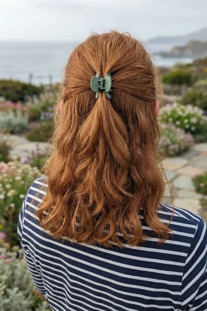 Claw clip half-up on shoulder-length wavy copper hair with a small sage green claw clip